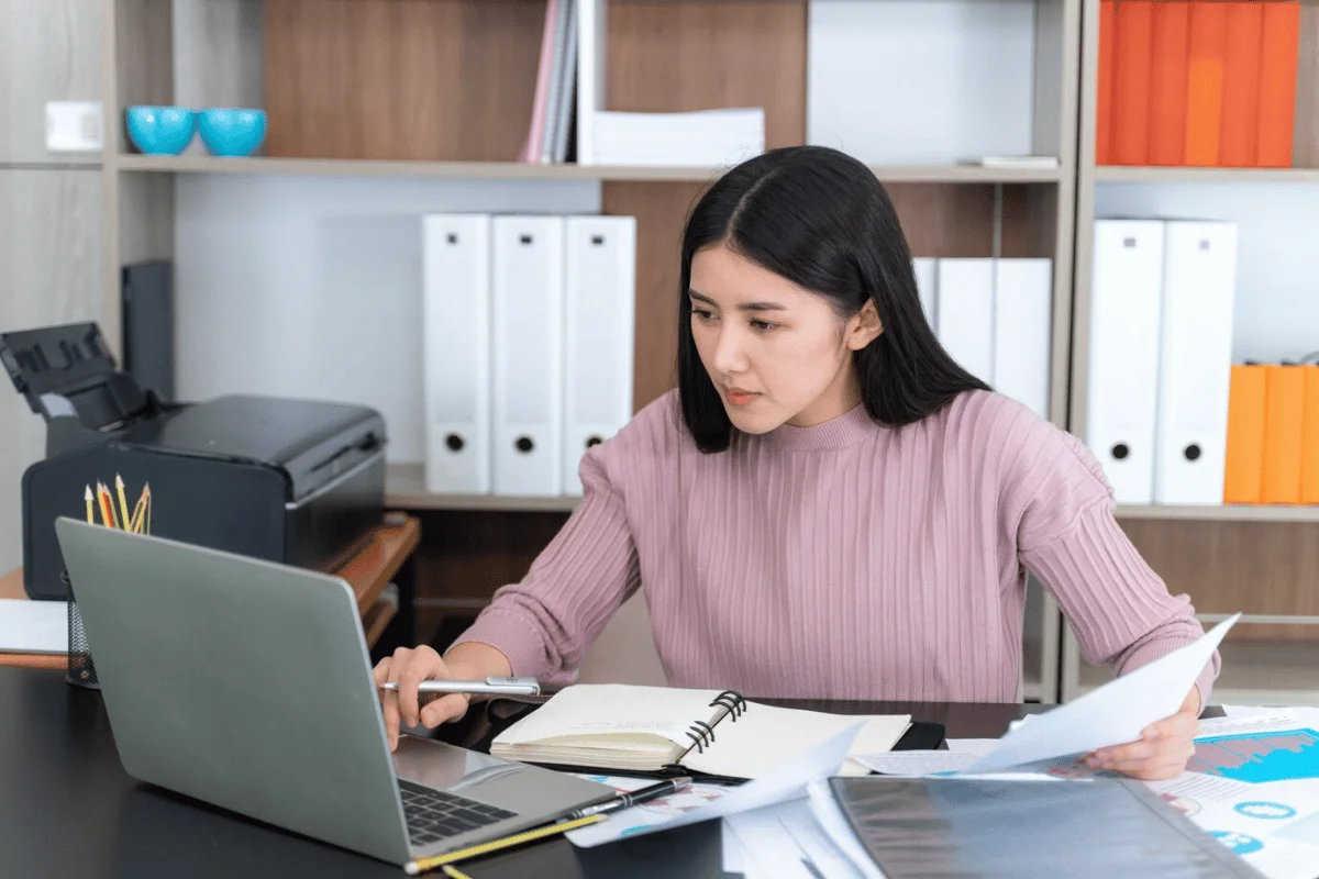 Focused woman analyzing financial documents at her desk.