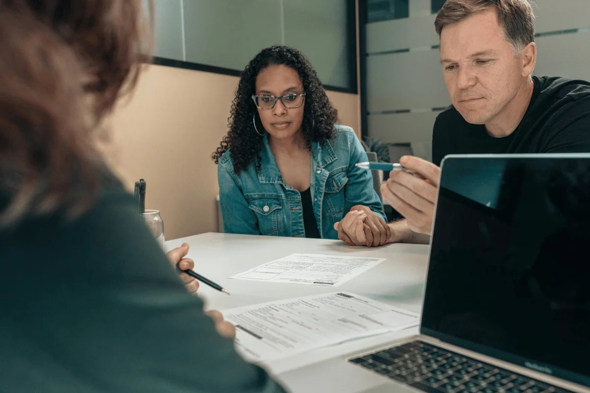 A couple attentively reviews documents with a consultant across the table.