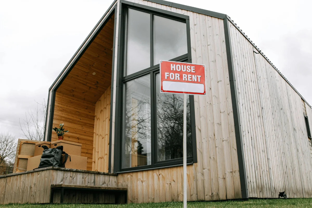 Modern wooden house with house for rent sign.