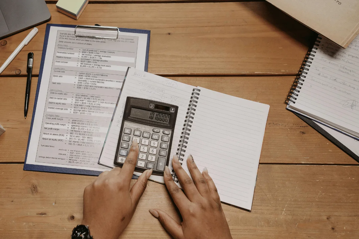 Person using a calculator with financial formulas on clipboard.