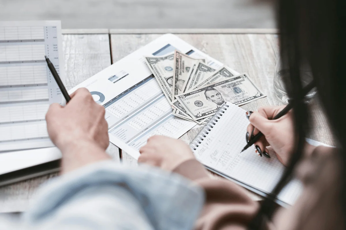 People reviewing financial charts with US dollar bills on table.