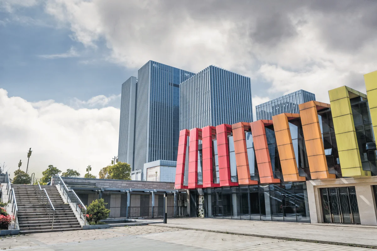 Urban architecture with tall blue office towers and a rainbow-colored structure.