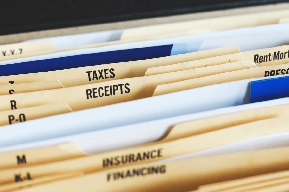 Close-up of organized file folders labeled "Taxes," "Receipts," "Insurance," and "Financing." Conveying organization and financial management.