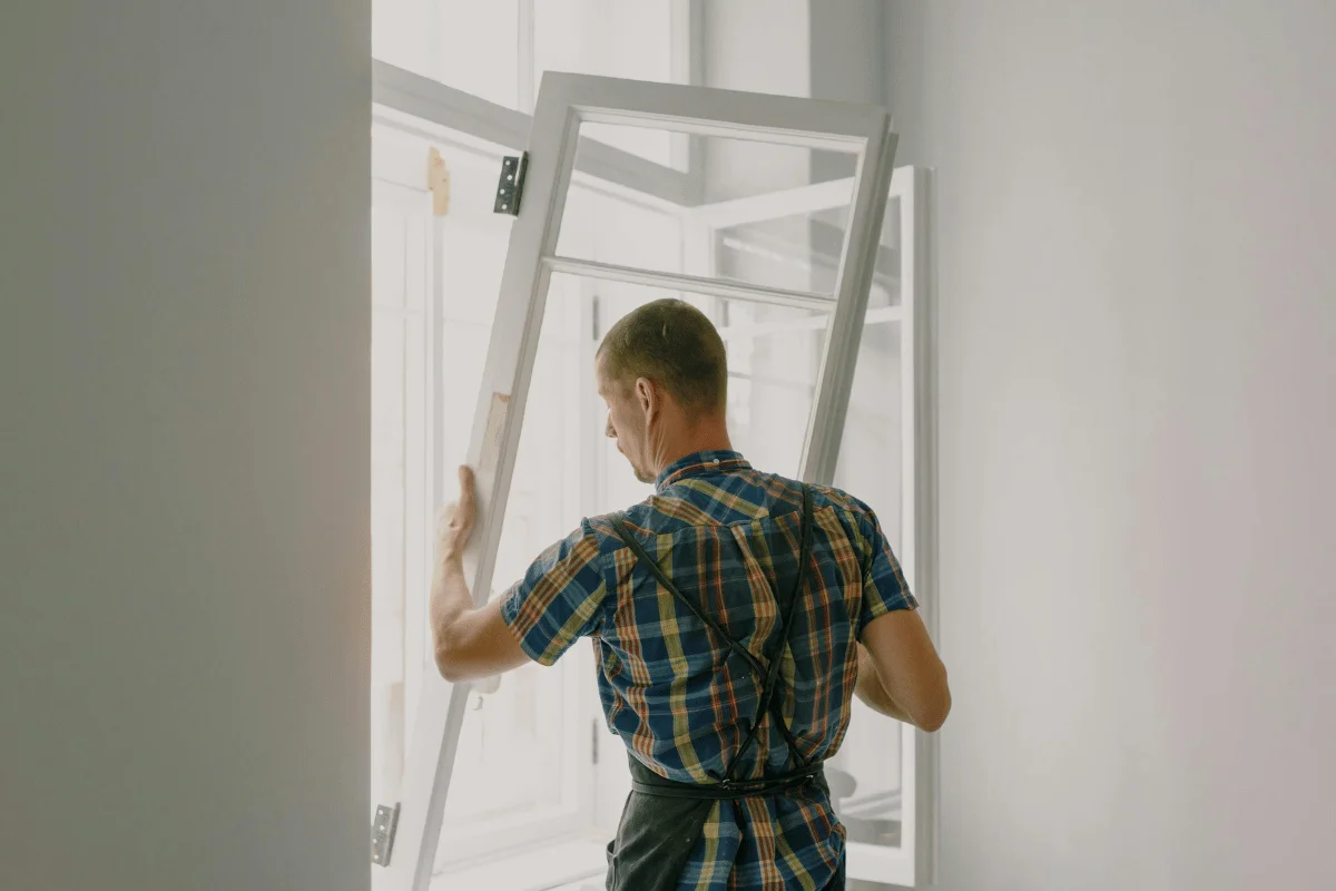 Worker installing or adjusting a white window frame in a modern home interior.
