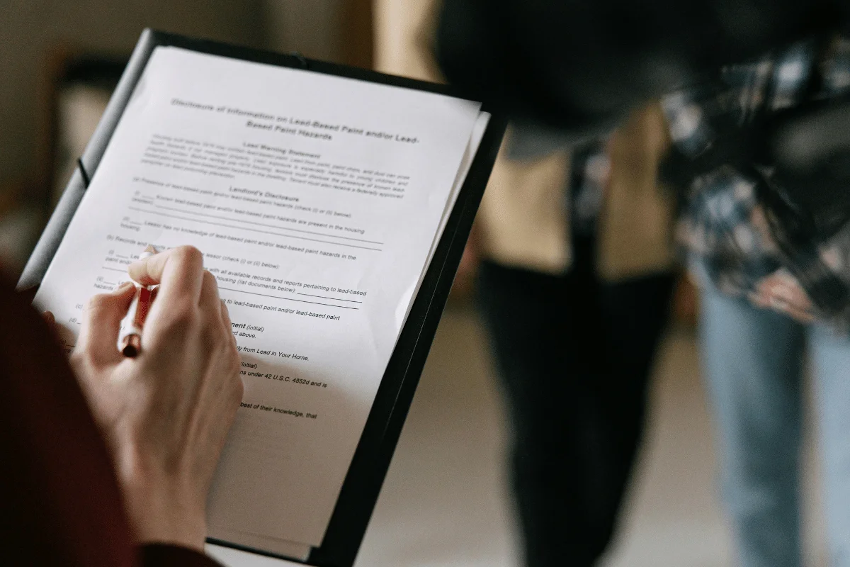 Person reviewing and signing official real estate or housing disclosure documents.