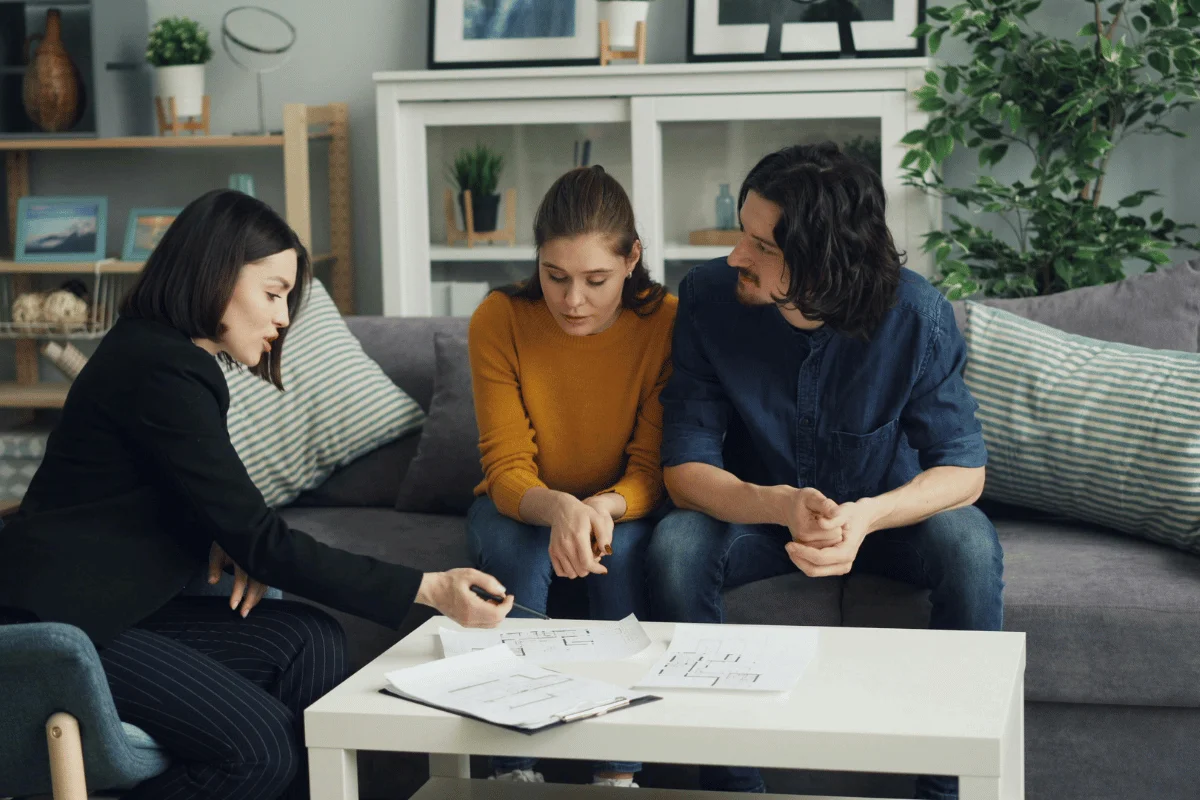 A couple reviewing floor plans with a real estate agent in a cozy living room setting.