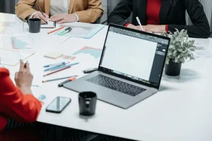 Office workspace with laptop, graphs, coffee mugs, and planners