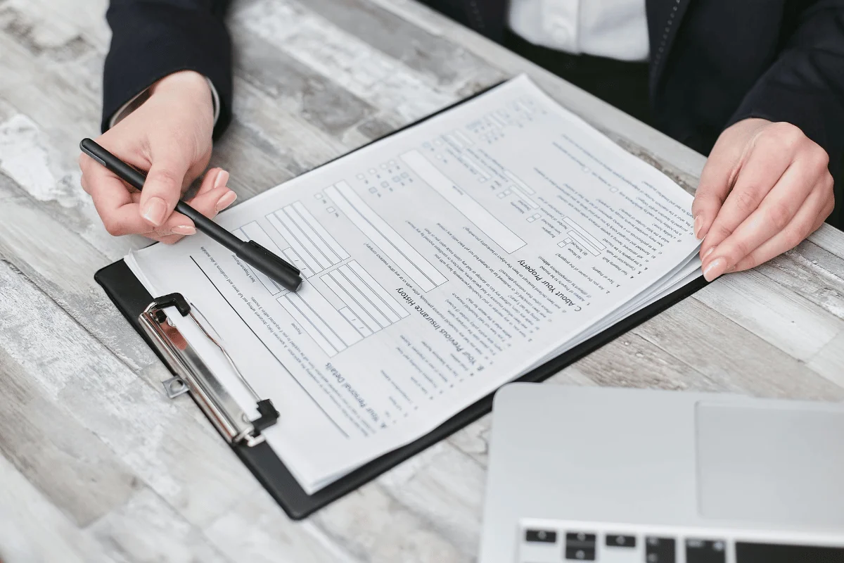 Person reviewing a document on a clipboard while holding a black pen.