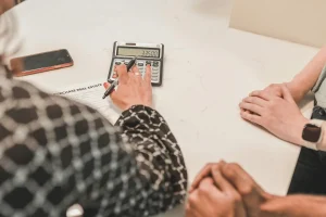 People reviewing a real estate purchase document with calculator on a countertop.