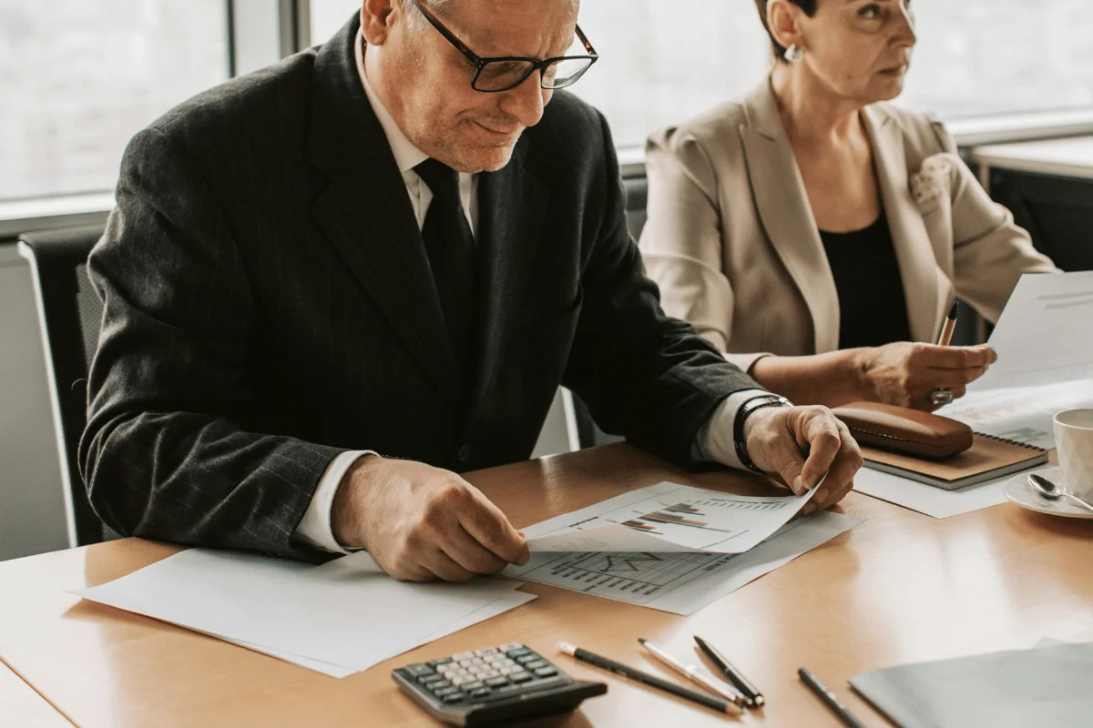 Man in suit reading printed financial reports.