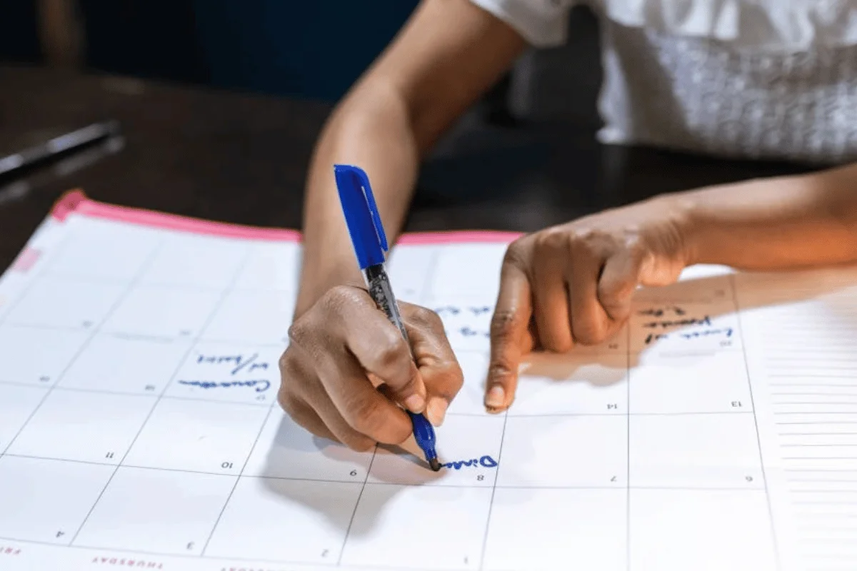 Woman writing on cost segregation new construction acquisition timeline chart with blue pen at wooden desk.